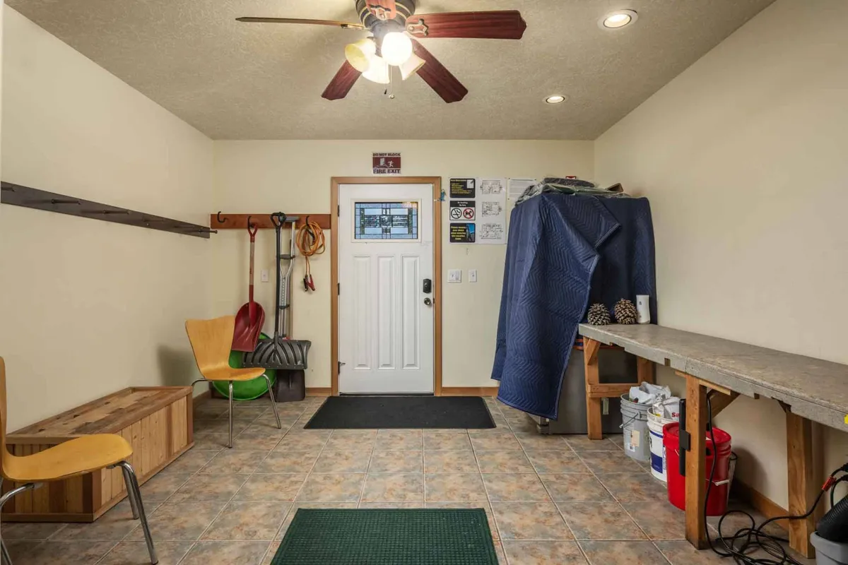 This image showcases the entryway area with a front door, a workbench, a seating area, and a wall lined with storage. The space is organized and functional, suggesting readiness for outdoor activities, with plenty of room to store gear and prepare for excursions.