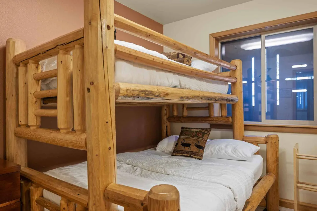 A compact, cozy nook with a bunk bed, decorative pillow, and a window providing natural light. The intimate setup is perfect for children or solo guests seeking a quiet retreat.